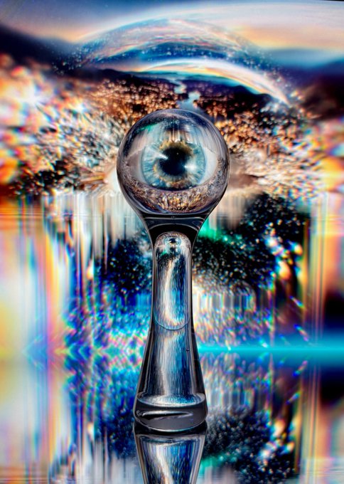 A surreal digital artwork showing a glass sphere containing a human eye, mounted on a stand with vibrant rainbow-colored liquid splashes and reflections creating a psychedelic effect.