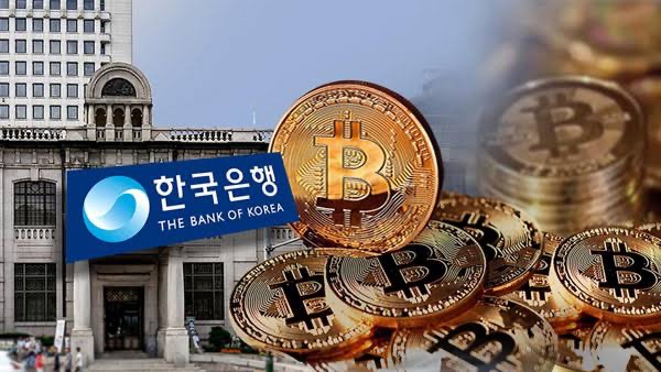 The image shows the Bank of Korea building alongside the bank's logo (한국은행 / "The Bank of Korea") overlaid with golden Bitcoin tokens, visually representing South Korea's move to tokenize government bonds on blockchain through its institutional CBDC pilot as described in the post.
