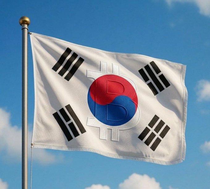 A photograph of the South Korean national flag, the Taegeukgi, waving on a flagpole against a blue sky with white clouds.