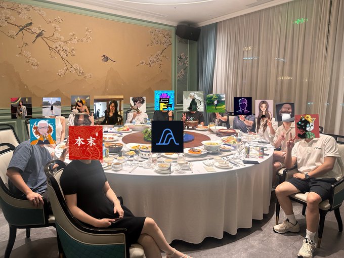The image shows a group of people sitting around a dining table with plates of food in front of them, suggesting that they have just finished eating or are about to start a meal together. The room has a large window behind the table, allowing natural light to illuminate the space and create an inviting atmosphere for socializing. The people at the table appear to be engaged in conversation, possibly discussing their work with @variational_io, as indicated by the post they have just read or seen.