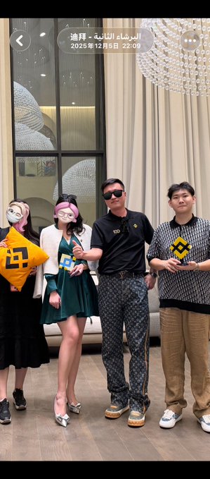 A photo dated December 5, 2025, from Dubai shows four people posing together, with one woman wearing an animal mask and another holding a yellow pillow featuring a Bitcoin-style "₿" logo. The post jokingly refers to "Wang Yuan" (likely Wang Yunfeng, the prominent Bitcoin bull known as "Sun Yuchen" associate), claiming to have met this wealthy and handsome crypto figure in person and expressing regret at missing a free hot pot meal in Chengdu.