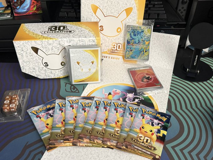 A Pokémon TCG "30th Anniversary Celebration" collection box is displayed with booster packs, a Player's Guide, a Lucario V card, and a black Pikachu promo, celebrating the release day pulls mentioned in the post.
