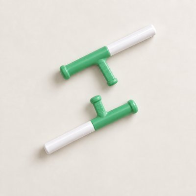 Two green and white toy water guns or squirters arranged on a light beige background.