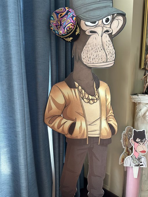 The image features a cartoon monkey wearing a yellow jacket, standing against a blue curtain backdrop. The monkey appears to be posing for a picture or participating in an event related to the "I bought trippy captain hat @the next ape fest you will see me in this hat More fun in NFTs @BoredApeYC". This suggests that there might be an upcoming event, possibly involving the cartoon monkey and other characters from popular culture. The post also mentions a pink tube with a cartoon character on it, which could be related to the event or simply serve as decoration for the occasion.

The image is accompanied by text that reads "I bought trippy captain hat @the next ape fest you will see me in this hat More fun in NFTs @BoredApeYC". This implies that the post might be promoting a specific product, such as the cartoon monkey's hat or other items related to the event. The image also includes a caption about an NFT (NFT) for the character at the next ape fest you will see me in this hat More fun in NFTs @BoredApeYC". This could be a reference to the NFT market, where people can buy and sell digital art or collectible items.