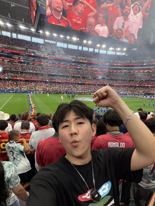 A young fan poses triumphantly with a raised fist at a packed soccer stadium during the World Cup, where fans around him wear jerseys—one clearly displaying "RONALDO." The image visually underscores the post's claim about the $ADI ecosystem's widespread presence in World Cup media and global sporting events.