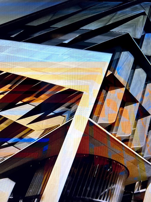 Abstract architectural photograph showcasing angular geometric beams and metal structures in a palette of blues, golds, and rust tones.