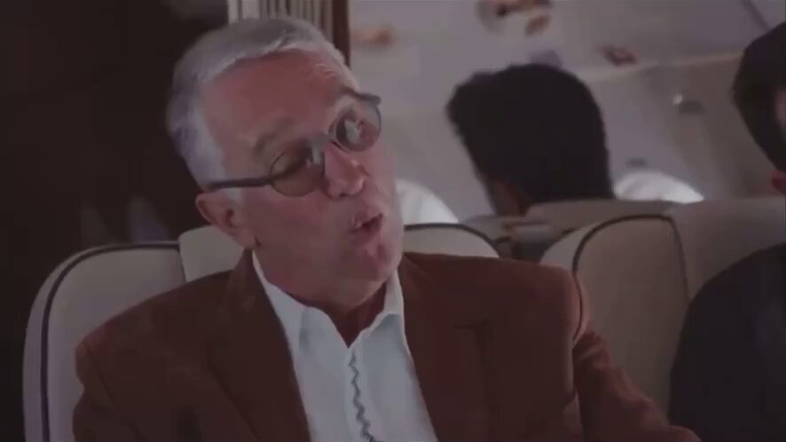 The image features a man wearing glasses sitting in an airplane seat with his head tilted back, looking out of the window. The background shows another person seated next to him, but they are not the main focus of the scene. The image also contains text that reads "Mexican Billionaire Ricardo Salinas said, 'once you have individuals free with their own monetary assets, it's very hard to make them into slaves.
 Fiat fraud is what facilitates the current day slavery." This message seems unrelated to the man sitting in the airplane seat and adds an interesting detail to the image.