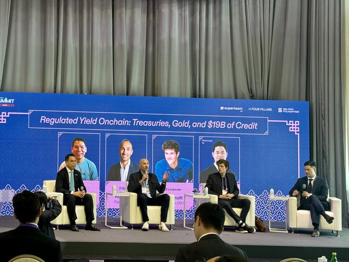 A panel discussion on a stage features four seated speakers in front of a blue backdrop titled 'Regulated Yield Onchain: Treasuries, Gold, and $19B of Credit,' with logos for Superteam, Four Pillars, and Sui Foundation visible.