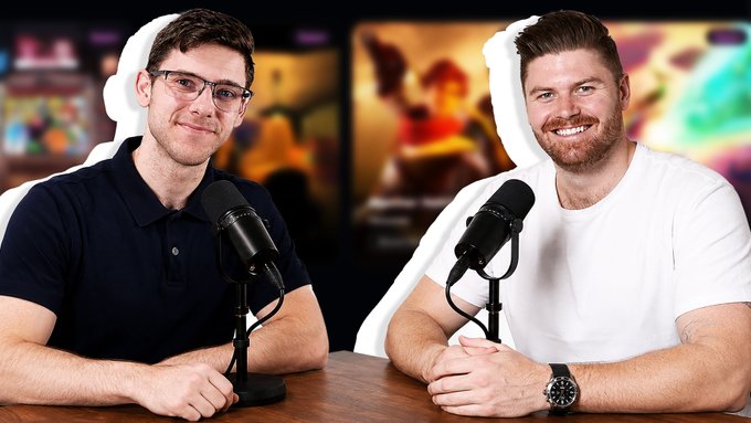 The image features two men sitting at a table, each holding a microphone. They are both smiling for the camera while appearing to be engaged in an interview or discussion. The background of the image shows a TV screen displaying various images, suggesting that they might be discussing something related to media or entertainment. The post includes information about an upcoming AMA with @KieranWarwick and details about his new project called "Loadout".
