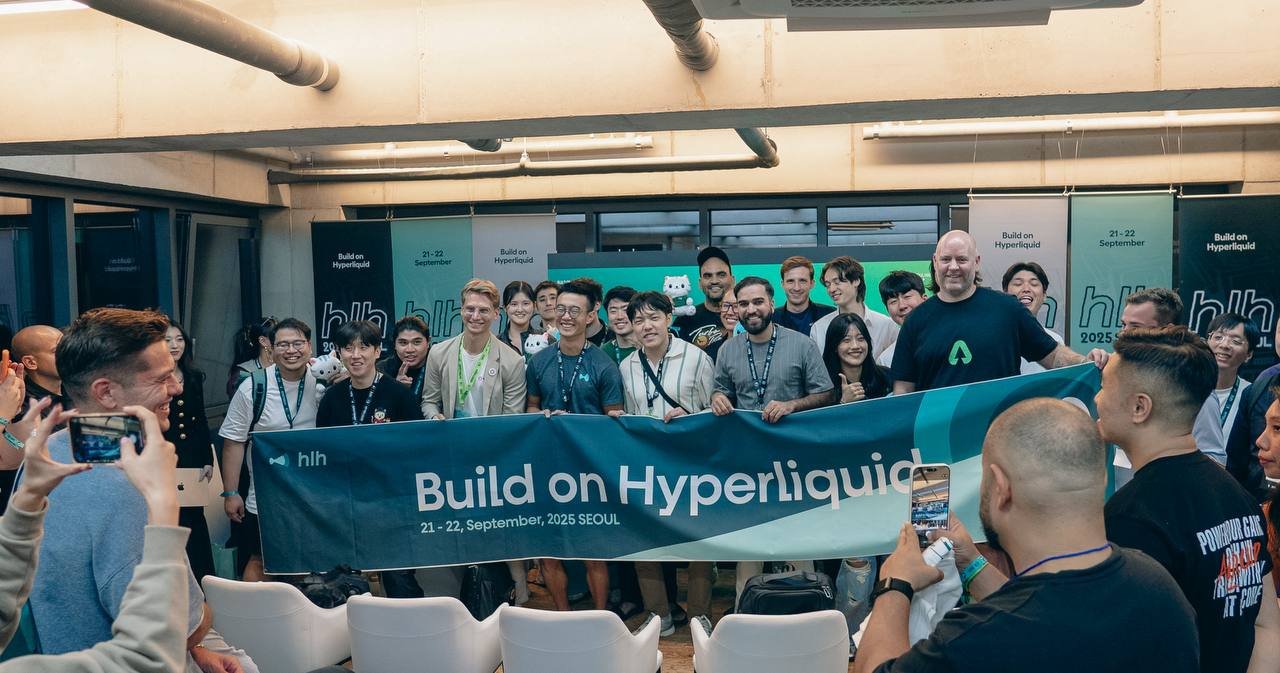 A large group of attendees poses for a photo holding a "Build on Hyperliquid 21-22, September, 2025 SEOUL" banner at a tech event, with several people taking photos with their phones.
