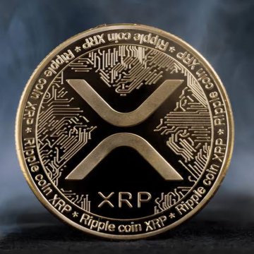 A close-up image of a gold XRP Ripple cryptocurrency coin with its distinctive 'X' logo and circuit board design.