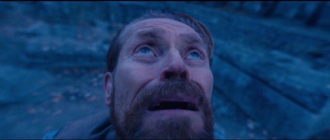 A bearded man with a shocked, upward-gazing expression in a dimly lit scene with bluish lighting, appearing to be from a film or cinematic shot.