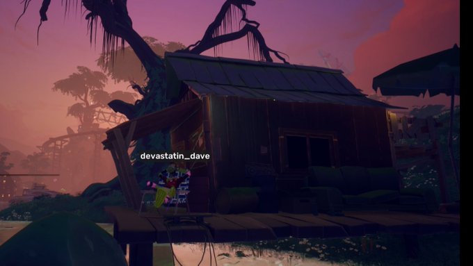 The image features an old, dilapidated wooden house situated in a forest setting. The house appears to be abandoned or in need of repair due to its worn-out appearance. A tree with long hanging branches can be seen nearby, adding to the overall atmosphere of the scene. In addition to the house and tree, there are two people present in the image - one person is standing near the left side of the frame, while another individual is located more towards the center. The post also includes a message that reads "flew with pigeons through the treetops, met with some robots in a secret cave then rolled some bones for monke coins with @mx170933937 just another day on @OthersideMeta gn you Damn Dirty Apes".