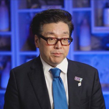 An Asian man wearing a black suit, blue tie, and black-rimmed glasses with a 'GRILL' lapel pin appears on a blue-toned television set.