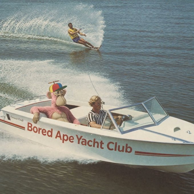 The image shows a woman waterskiing behind a speedboat, with a large pink cartoon ape wearing a propeller hat sitting beside the driver. The boat is labeled "Bored Ape Yacht Club" along its side, playfully illustrating the NFT brand's yachting aesthetic.