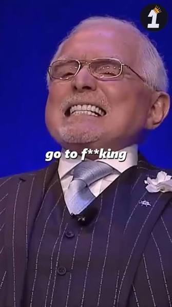 A TV screenshot showing an older man in a pinstripe suit and glasses laughing, with caption text reading 'go to f**king' and a channel '1' logo in the corner.