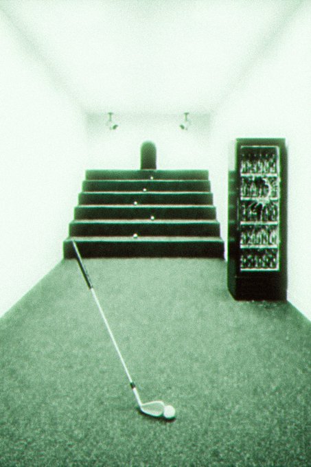 A blurry, vintage-style photograph of an indoor golf simulator room with steps, a tee, and a golf club lying on the carpet.