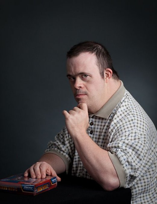 A man in a checkered polo shirt sits with a contemplative expression, his hand resting on his chin in a classic "thinking" pose, while his other hand grips a box of "Diplomat" game pieces. The image humorously captures the deliberation of "toly" (Anatoly Yakovenko, Solana's founder) weighing whether to support new projects on his blockchain or stick to his famous Twitter activity.