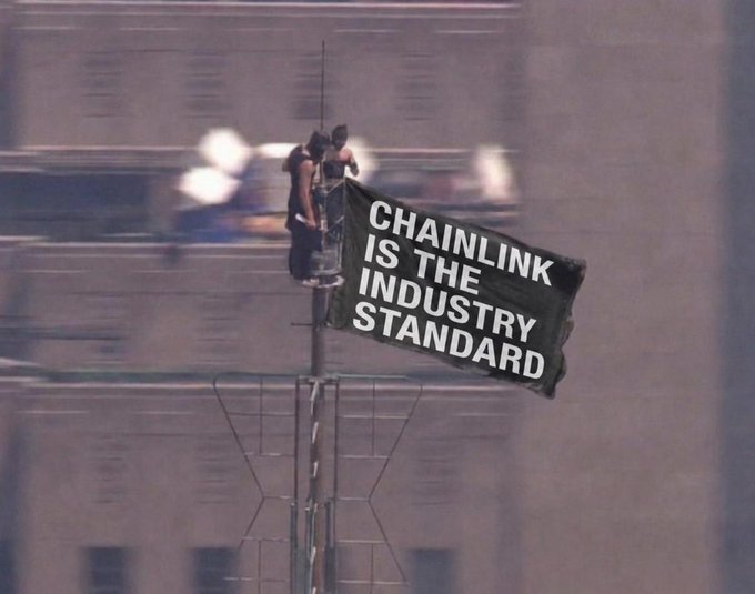 Two workers at the top of a tall structure unfurl a large black banner reading "CHAINLINK IS THE INDUSTRY STANDARD," visually reinforcing the post's claim that Chainlink (LINK) is positioning itself as foundational infrastructure on par with major tech giants like Microsoft.