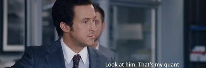 A still image of a man in a suit looking at someone off-camera with the subtitle text 'Look at him. That's my quant'.