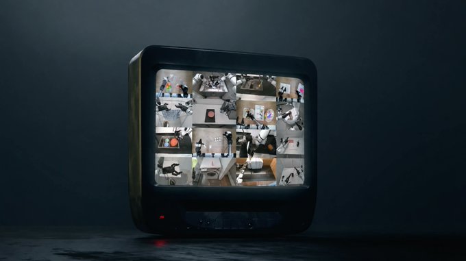 An old-school CRT television displays a multi-camera security feed grid of a robotics/automation workspace, where various robotic arms and equipment are visible in different rooms, tying into the post's theme of "Validator Watch Wednesday" by visually representing the monitoring and oversight of robotic teleoperation systems.