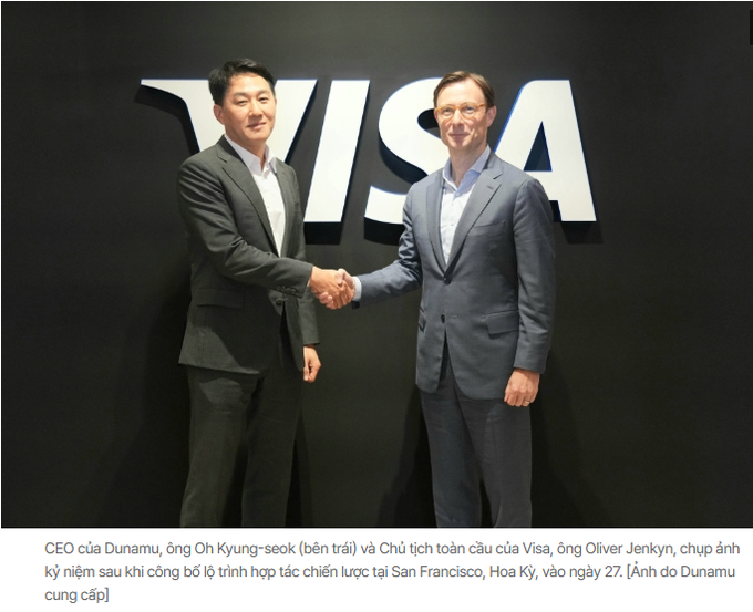 Two men shaking hands in front of a large VISA logo, with Vietnamese text below identifying them as Oh Kyung-seok (CEO of Dunamu) and Oliver Jenkyn (Visa Strategy Lead) at a strategic partnership signing in San Francisco on the 27th.