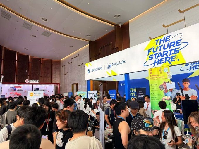 A crowded convention hall with attendees visiting booths, including 'Injective' and 'Ninja Labs' stands featuring a 'THE FUTURE STARTS HERE' banner.