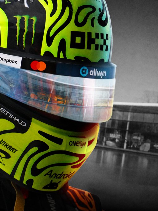 A close-up of a vibrant yellow and green racing helmet featuring sponsor logos including Monster, Dropbox, Mastercard, allwyn, Etihad, ONEflight, and Android, set against a black-and-white racetrack background. The high-energy motorsport imagery visually reinforces the post's message about "new ways to move" with a fresh, fast-paced financial app.