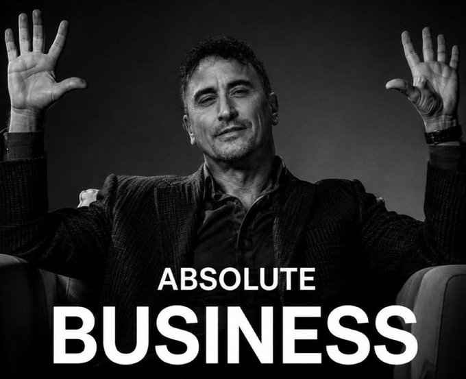 A black-and-white image of a man in a suit sitting in a chair with both hands raised, with the text 'ABSOLUTE BUSINESS' overlaid at the bottom.
