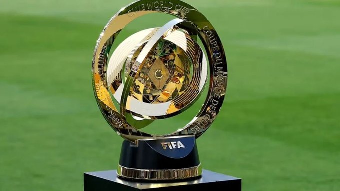 A golden FIFA Club World Cup trophy with a globe design sits on a black pedestal against a green grass background.