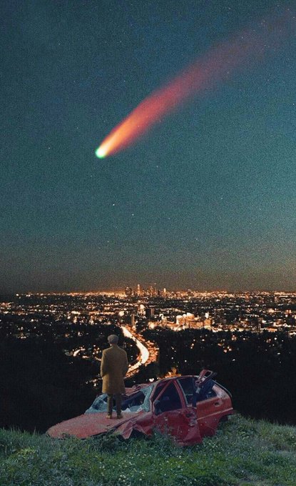 A cinematic nighttime scene shows a person in a coat standing by a wrecked red car on a hill, watching a green comet streak across the sky above a distant illuminated city.