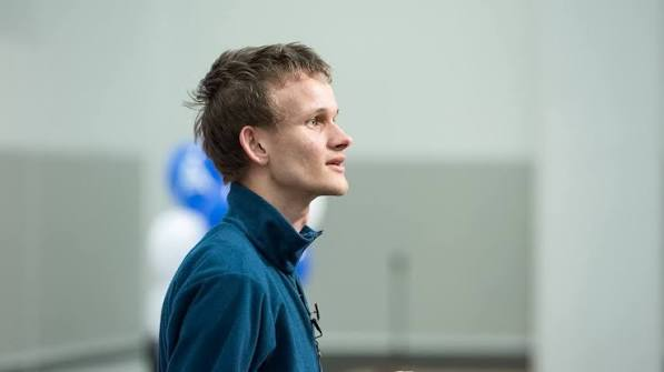 A side profile portrait of a man with short brown hair wearing a dark teal jacket, looking off to the side in a softly lit indoor setting.