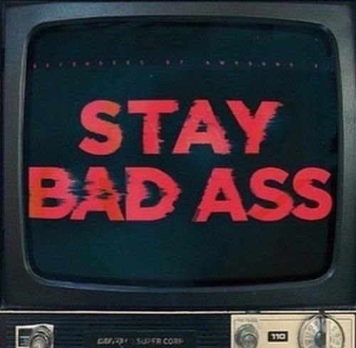 A vintage television set displaying the text 'STAY BAD ASS' in large, glitchy red letters on its screen.