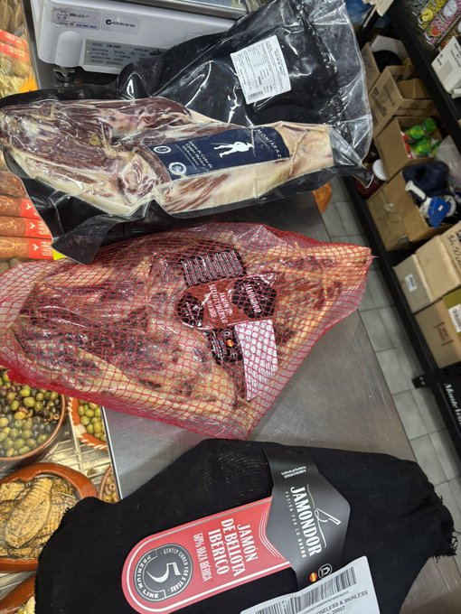 A photo of various packaged meats and a jamón de bellota 100% ibérico in a market setting.