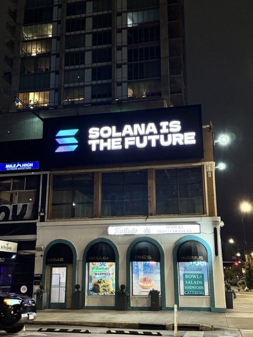 A nighttime photo of an illuminated digital billboard displaying the Solana logo and the text 'SOLANA IS THE FUTURE' above a Mediterranean restaurant called 'Kallisto'.