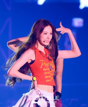A female performer with long brown hair wearing a red cropped tank top with 'Per...' text poses on stage. Watermarked 'CLOUD BLUE'.