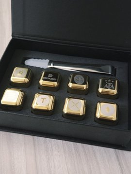 A black gift box displays eight stainless steel ice cubes engraved with cryptocurrency symbols including BTC, ETH, USDT, SOL, and XRP, alongside a matching pair of tweezers, presented as part of a Deepcoin giveaway promotion.