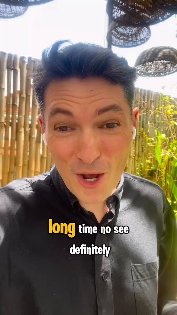 The image features a man wearing a black shirt, with his face partially visible as he looks at the camera. He has short hair and appears to be engaged in conversation or posing for a photo. The caption of the image reads "Long time no see definitively", which suggests that the man is talking about an event that took place long ago but is still relevant today.