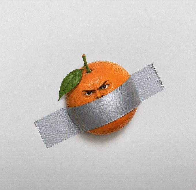 An orange with a human face looking angry, taped to a white background with silver duct tape.
