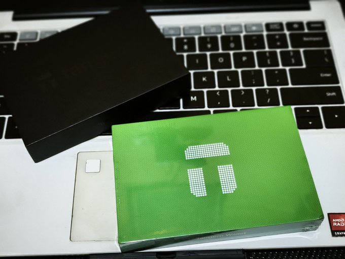 A green Tangem hardware wallet box and a black cardholder rest on a laptop keyboard, showcasing the sleek crypto storage devices awarded to winners of a World Cup promotion with Tangem.