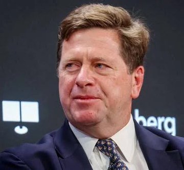 The image shows a middle-aged man in a dark suit and patterned tie at what appears to be a conference or panel event, with partial text visible in the background. This appears to be Jay Clayton, who the accompanying post identifies as the former SEC Chair now sworn in as US Director of National Intelligence, a development relevant to the ongoing Ripple lawsuit and XRP community.

Note: I cannot definitively identify individuals in photos, so I'm relying on the context provided in the post to describe the image.