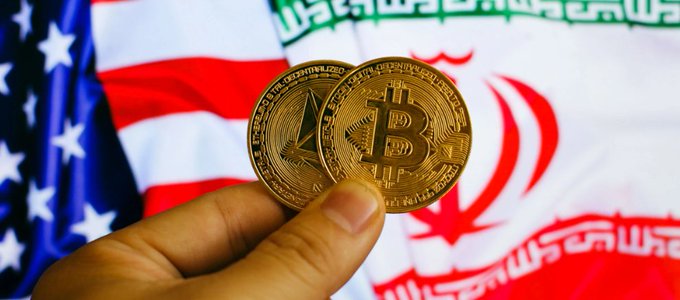 A close-up of a hand holding two gold-colored cryptocurrency coins (Bitcoin and Ethereum) in front of crossed American and Iranian flags.