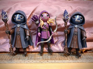 The image features three figurines of characters from a video game, each holding a bow and arrow. The figurines are standing next to each other against a pink background with a white curtain as their backdrop. The text "Couple characters just bout ready to be sent to the summit so be sure to whisper sweet nothings into @bitstoys ear for your chance to own one" is present, suggesting that these figurines might be collectibles or limited edition items related to the video game.