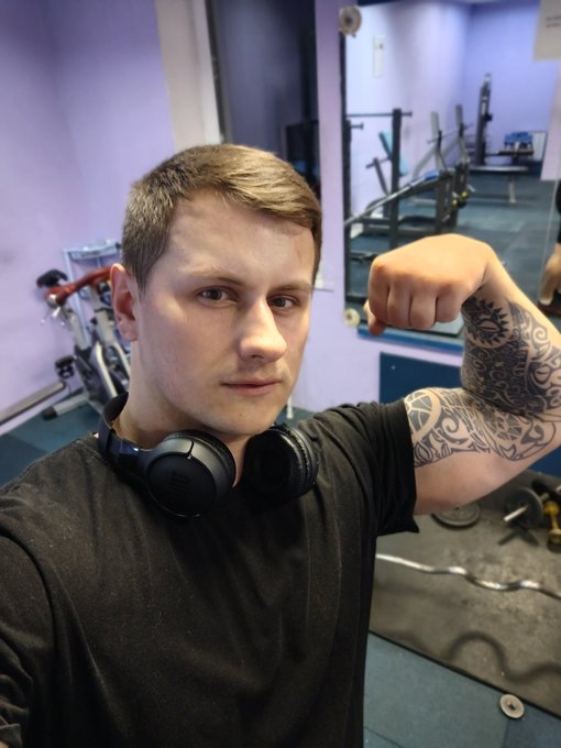 The image features a man wearing headphones, standing inside a gym with his arm raised above his head. He has tattoos on his arm and appears to be posing for a photo. The caption of the image reads "GA, quackers! The more time I spend @wallchain ecosystem, the more I start understanding why this project genuinely feels different from many other platforms in the same category A lot of Web3 social / attention projects focus almost entirely on surface-level metrics:".