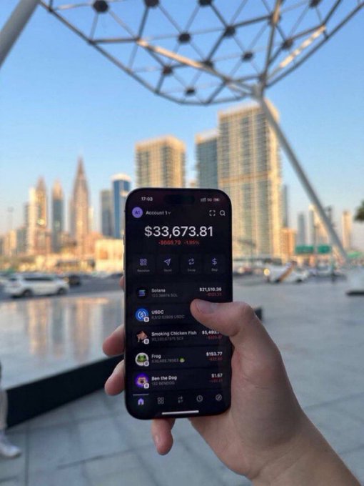 A hand holds a smartphone displaying a crypto portfolio showing $33,673.81 against a city skyline backdrop, visually reinforcing the post's message of future wealth through an upcoming airdrop event scheduled for September 24th at 1PM EST, where 75% of the token supply will be distributed to those who drop their $SOL wallet addresses.
