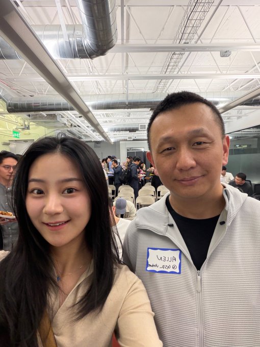 The image features two people, a man and a woman, standing close together with their arms around each other. They are both smiling for the camera. The caption of the image reads "I just gave @xiaohu_zhu a follow if you're a @BoredApeYC you should give him a follow too." This message is related to the post because it suggests that the woman might have tagged the man in her photo, and they are both following each other's posts.