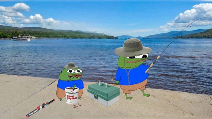 Two Pepe the Frog cartoon characters are fishing on a sandy shore beside a scenic lake with mountains in the background; one wears a wide-brimmed hat and blue shirt while casting a rod, and the other sits next to a green tackle box and a white bucket labeled "Catch Chum Blood Big Bait" (likely "Blood Red Big Bait"). The peaceful Sunday fishing scene matches the relaxed "Happy Sunday" vibe of the post.