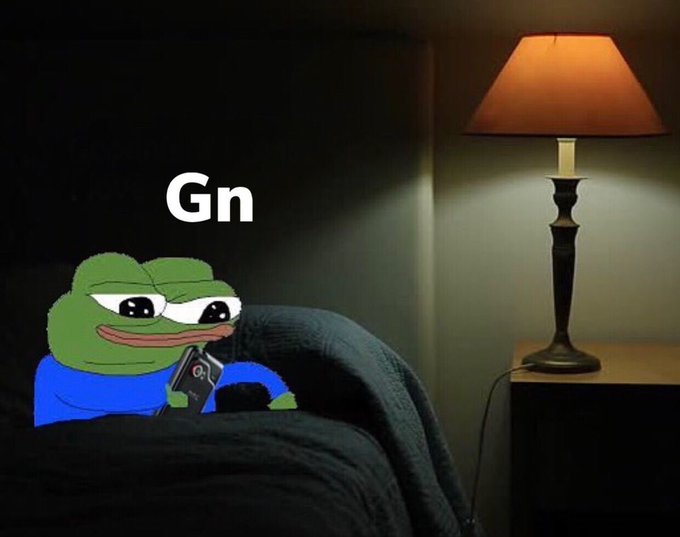 A meme image featuring a sad Pepe the Frog holding a phone in bed with 'Gn' (good night) text, set in a dimly lit bedroom with a lit lamp.