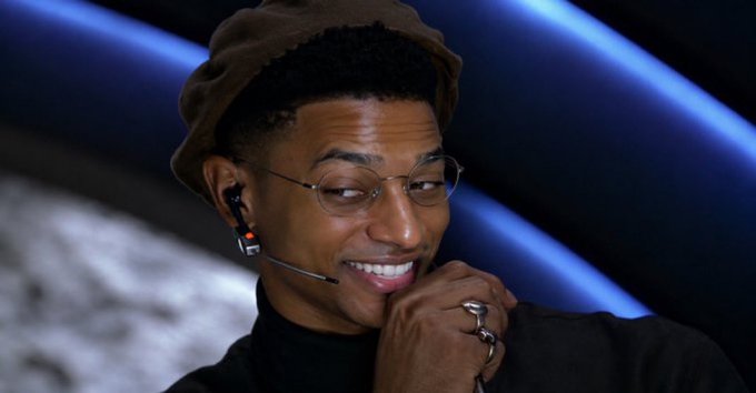 A smiling young man wearing a brown beanie, wire-rimmed glasses, and an earpiece rests his chin on his hand adorned with silver rings, appearing amused. The image of @blknoiz06, referenced as the one "saving the trenches," complements the post's optimistic crypto predictions about $ANSEM, $SOLANGELES, and an upcoming Pumpfun airdrop.