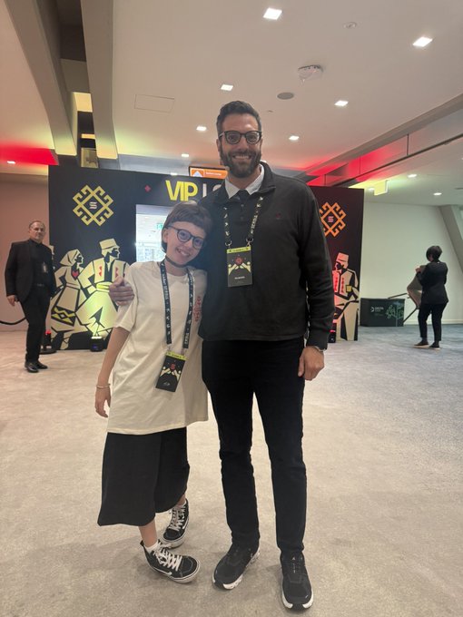The image shows a young person and an adult man posing together at what appears to be a Solana VIP event, both wearing VIP lanyards. They are smiling warmly at the camera, with the man giving a thumbs-up, reflecting the post's sentiment of being "so happy" to link with @SiaSkateson, "the best skateboarder and coolest girl on Solana."